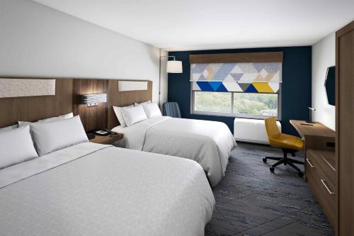 Holiday Inn Express & Suites - Phoenix West - Tolleson, an IHG Hotel في فينكس: غرفة فندقية بسريرين ونافذة