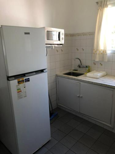 eine Küche mit einem weißen Kühlschrank und einer Mikrowelle in der Unterkunft Casa El Ceibo Reserva con Seña in Piriápolis