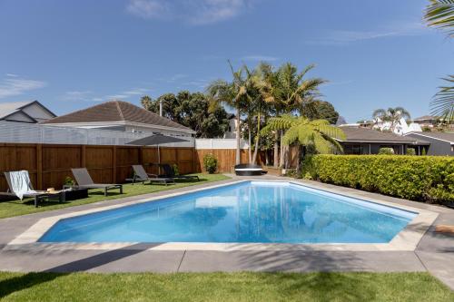 a swimming pool in the yard of a house at Cobblestone Court Motel - Wenzel Motels in Tauranga