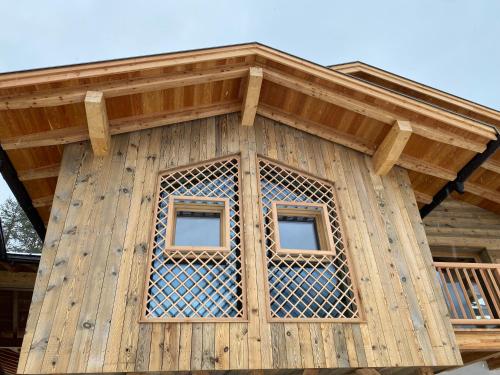 a wooden building with two windows on it at Les Ciases Chalets Dolomites in San Vigilio Di Marebbe