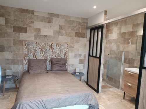 a bedroom with a bed and a stone wall at Gîtes les Bernes in Saint-Pardon-de-Conques