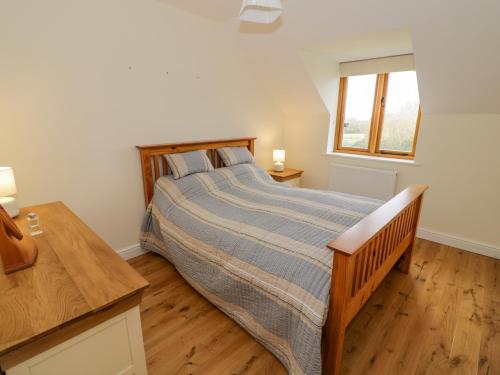 een slaapkamer met een bed, een bureau en een raam bij The Granary in Southam
