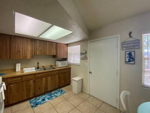 a kitchen with wooden cabinets and a sink and a door at Professor Rousseau's Mermaid Lagoon in Crystal River