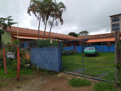 uma cerca em frente a uma casa com uma palmeira em suítes Bomfass em Alto Paraíso de Goiás