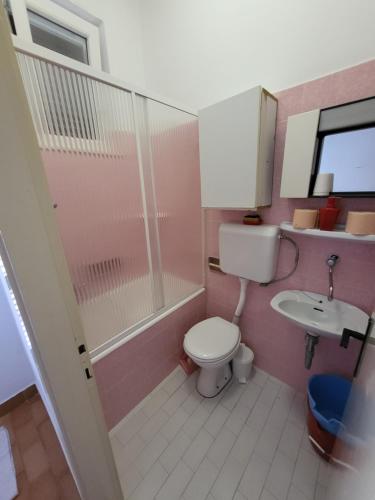 Baño de color rosa con aseo y lavamanos en Island Paradise Apartment, en Kukljica