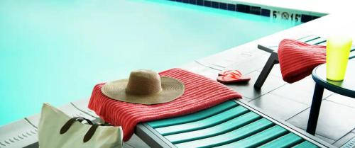 Home2 Suites By Hilton Dallas Medical District Lovefield, Tx في دالاس: وجود قبعة على كومه من المناشف بجانب المسبح