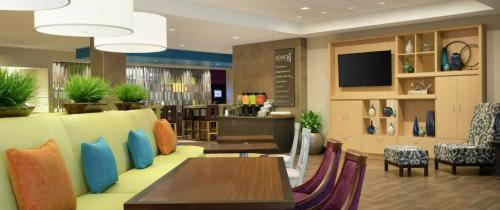 a restaurant with tables and chairs and a tv at Home2 Suites By Hilton Dallas Medical District Lovefield, Tx in Dallas