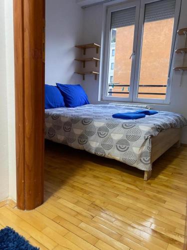 a bedroom with a bed and a large window at Tea Apartment in Skopje