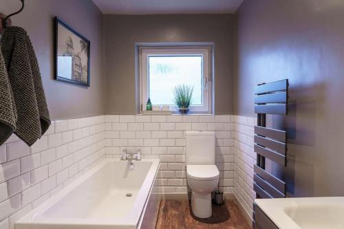 ein Bad mit einer Badewanne, einem WC und einem Fenster in der Unterkunft Smart self-catering apartment, Clitheroe in Clitheroe