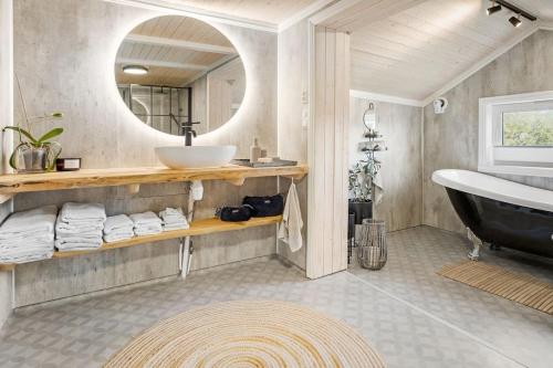 een badkamer met een wastafel, een bad en een spiegel bij Koselig bolig i Lofoten / Vesterålen in Strønstad