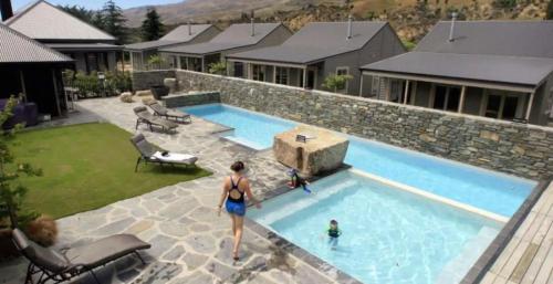 Cardrona Mountain Chalet with Pool and Jacuzzi في Cardrona: امرأة تقف بجوار حمام السباحة في منزل