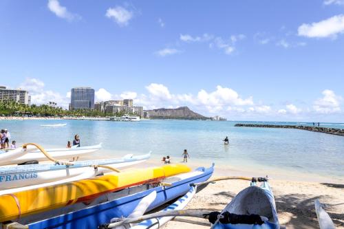 un groupe de bateaux sur une plage avec des gens dans l'eau dans l'établissement Apartments at Palms Waikiki, à Honolulu