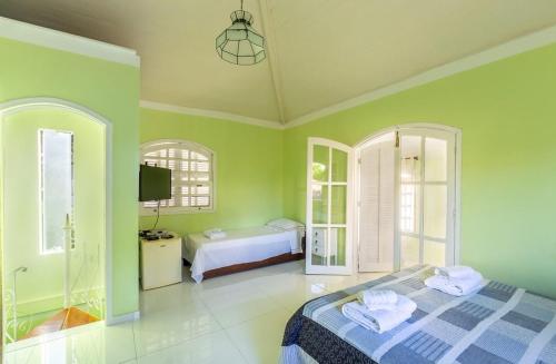 Búzios Casa Verde في بوزيوس: غرفة نوم خضراء بها سرير وتلفزيون