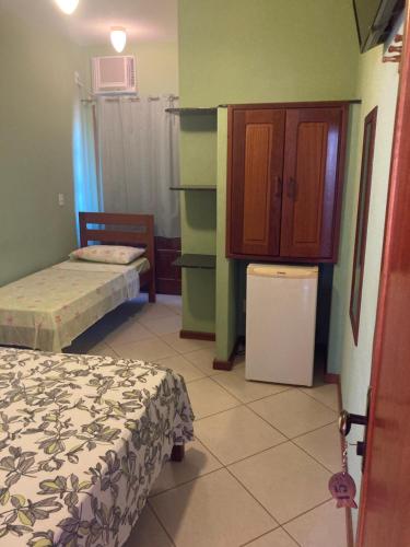 a small room with two beds and a refrigerator at Pousada Maravista in Anchieta