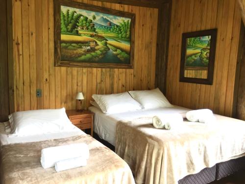 two beds in a room with wooden walls at Cabana com vista para o canyon in Praia Grande