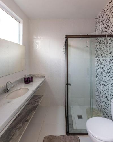 a bathroom with a shower and a sink and a toilet at Búzios Casa Verde in Búzios