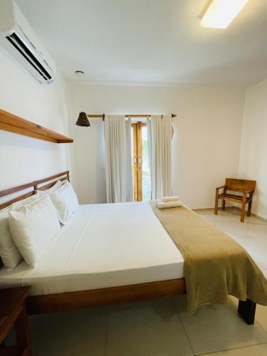 a bedroom with a large white bed with a chair at Villa Mar Residence in Jericoacoara