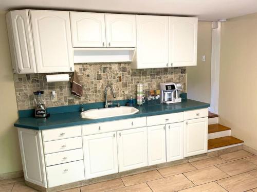 a kitchen with white cabinets and a sink at Forest and River Side Tranquil House in Montague