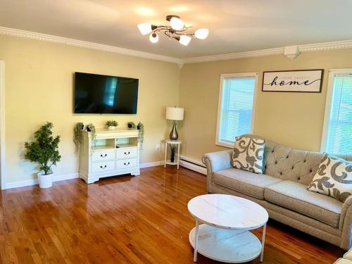 a living room with a couch and a tv at Forest and River Side Tranquil House in Montague