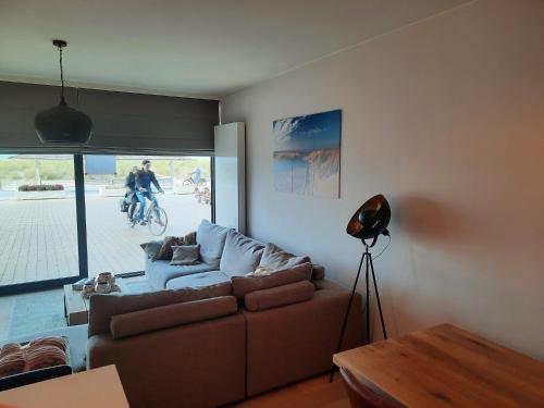 una sala de estar con sofá y una persona en bicicleta en lectus IV en Nieuwpoort