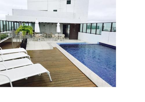 a pool in a building with chairs and a table at Beach Class Santa Maria by Easy Home in Recife