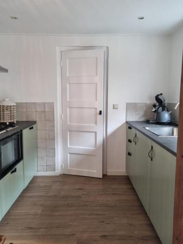 a kitchen with white cabinets and a white door at cottage near the beach in the center.**** in Noordwijk aan Zee