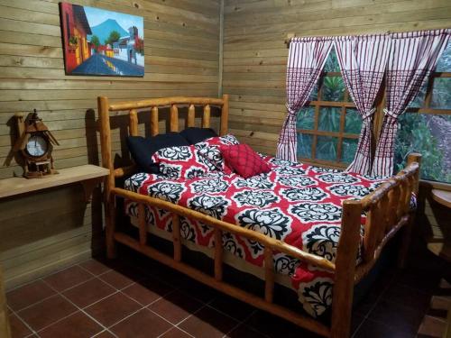 a bedroom with a wooden bed with a red and white blanket at Chalet in the Woods in Santiago Atitlán