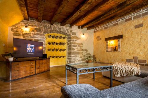 a living room with a tv and a stone wall at Villa Kotli Stone House in Kotli