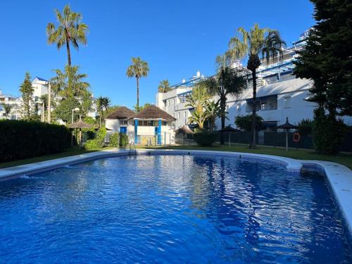 a large swimming pool in a yard with palm trees at Apartamento en Costa Ballena, Urb. Playa Ballena in Cádiz