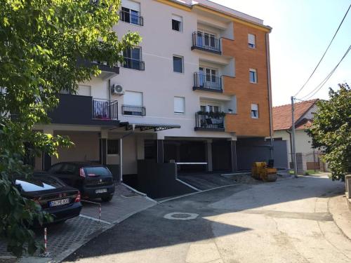 ein weißes Gebäude mit einem davor geparkt in der Unterkunft Apartmani S - DSN in Kraljevo
