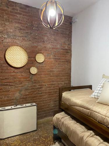 a bedroom with a brick wall with two beds and a chandelier at Inti, hospedaje de campo. in Bartolomé Mitre