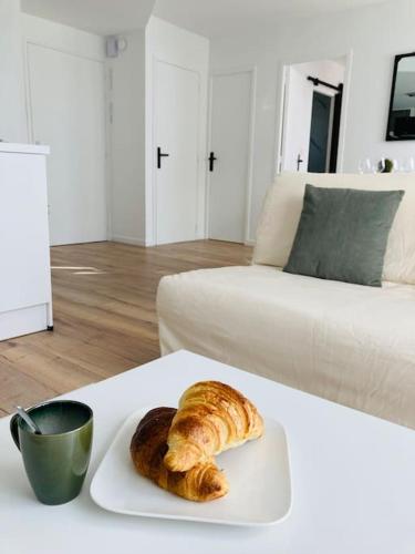 a plate with a croissant and a cup on a table at Le Coconing Moderne Centre Saint-Sébastien-sur-Loire, proche de Nantes in Saint-Sébastien-sur-Loire