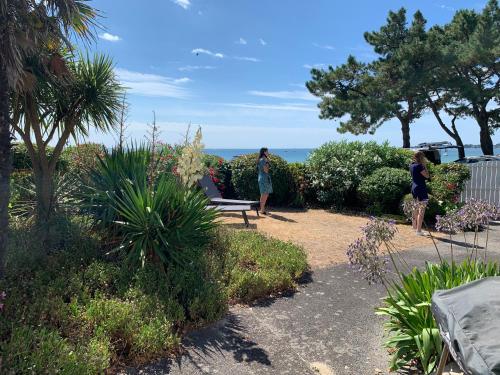 2 personnes debout dans un jardin avec l'océan en arrière-plan dans l'établissement Maison sur la pointe du Cap Coz, à Fouesnant