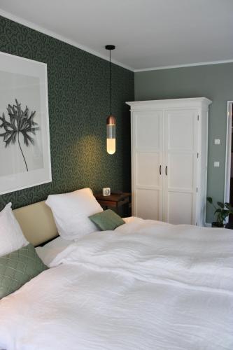 1 dormitorio con cama blanca y pared verde en Ferienwohnung GeestZuhause en Heeslingen