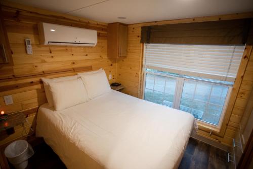 1 dormitorio con cama blanca y ventana en Lake George Escape, en Warrensburg