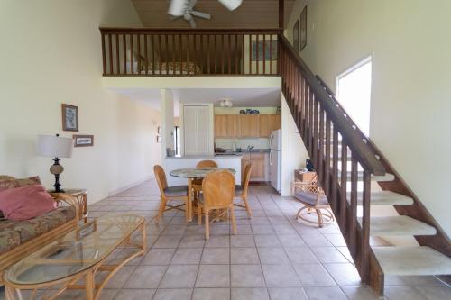 a living room with a staircase and a table and chairs at Takanoha Condo in Kahuku