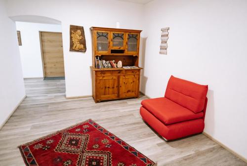 uma sala de estar com uma cadeira vermelha e um tapete em Gasthof Franziskibad em Bad Häring