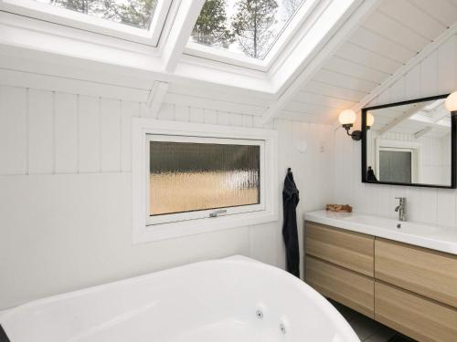 ブラーバンドにあるFour-Bedroom Holiday home in Blåvand 42の白いバスルーム(バスタブ付)、窓が備わります。