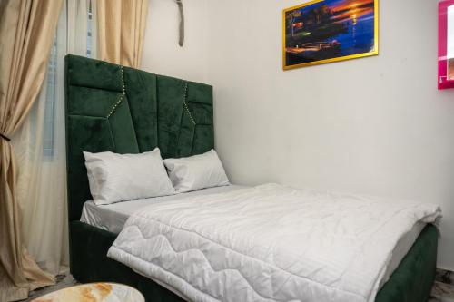 a bed with a green headboard in a room at Discover 8-Bedrooms Lakeside Apartment Living Free Starlink SuperFast Speed WiFi And Well Secured in Amuwo