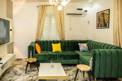 a living room with a green couch and tables at Discover 8-Bedrooms Lakeside Apartment Living Free Starlink SuperFast Speed WiFi And Well Secured in Amuwo