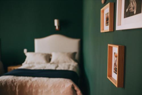 Dormitorio verde con cama y cuadros en la pared en Anden Inca Hotel, en Cusco
