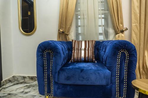 a blue chair with a pillow in a room at Discover 8-Bedrooms Lakeside Apartment Living Free Starlink SuperFast Speed WiFi And Well Secured in Amuwo