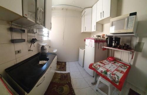una pequeña cocina con armarios blancos y encimera negra en Apartamento em Curitiba completo e perto de tudo, en Curitiba