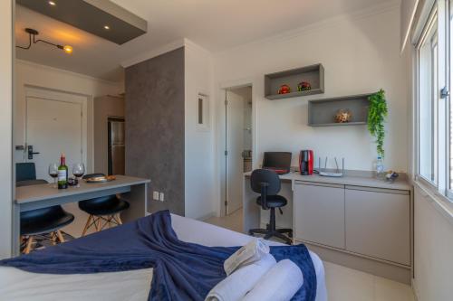 een slaapkamer met een bed, een bureau en een keuken bij OFERTA! Ensolarado no 13º andar CENTRAL Próx IMED Garagem in Passo Fundo