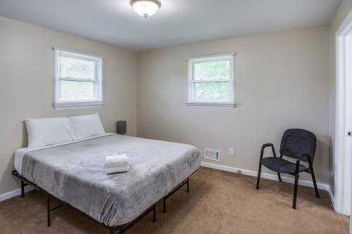 een slaapkamer met een bed en een stoel erin bij {Quiet Suburban Ranch Hot Tub} Mins Arpt/RIT/DWNT in Rochester