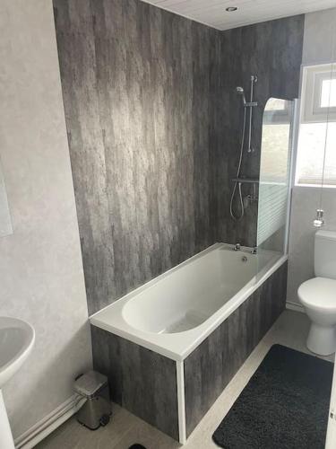 a bathroom with a tub and a toilet and a sink at Fantastic full 3 bedroom modern apartment in Belfast