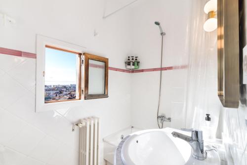 ein weißes Badezimmer mit Waschbecken und Fenster in der Unterkunft Historic penthouse Plaza Mayor in Madrid in Madrid