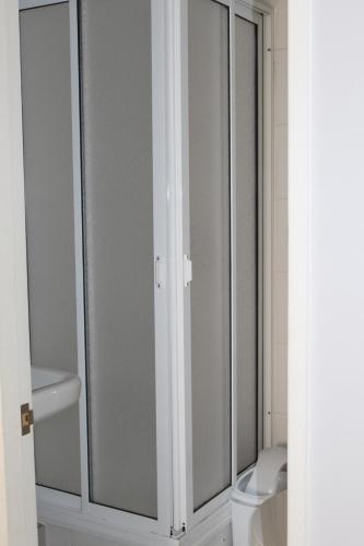 a bathroom with a toilet and a glass shower door at Departamento Familiar los Molles in Los Molles
