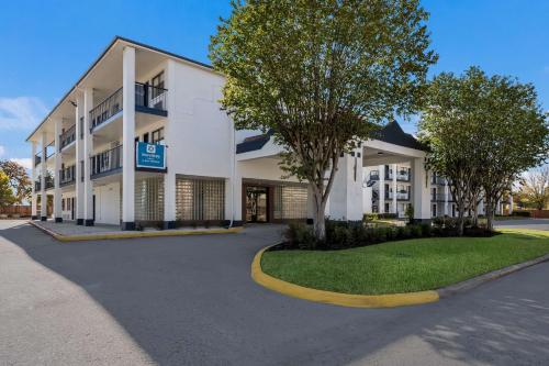 a white building with trees in front of it at SureStay Hotel by Best Western Spring North Houston in Spring
