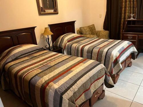 a bedroom with two beds and a chair at Casa Villa Serena in San Carlos